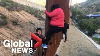 Migrant families continue to spill over Tijuana border fence head to US [upl. by Ahsilyt124]